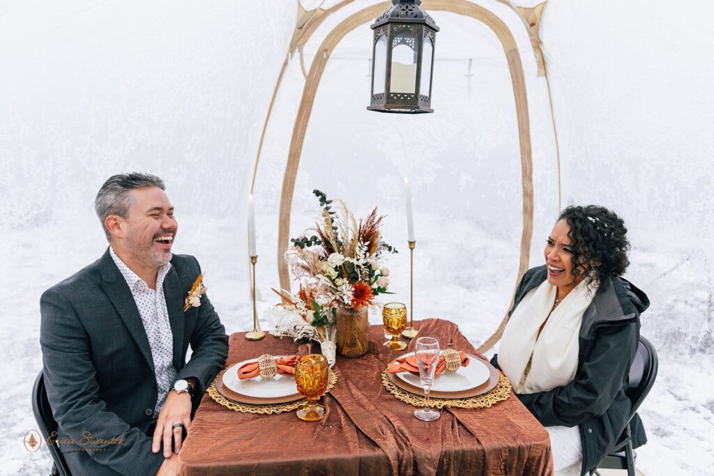 bride and groom enjoying their boho styled picnic under a clear tent set for their winter elopement in columbia river gorge