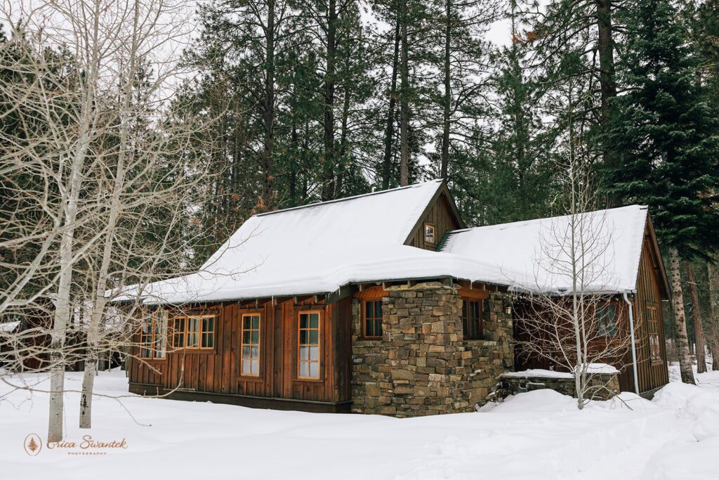 A rustic cabin surrounded by snow, with a beautiful layer of snow covering its roof