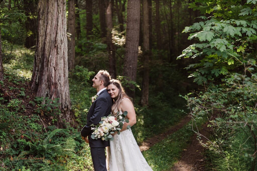 bride and groom hiking together through a lush forest in Oregon