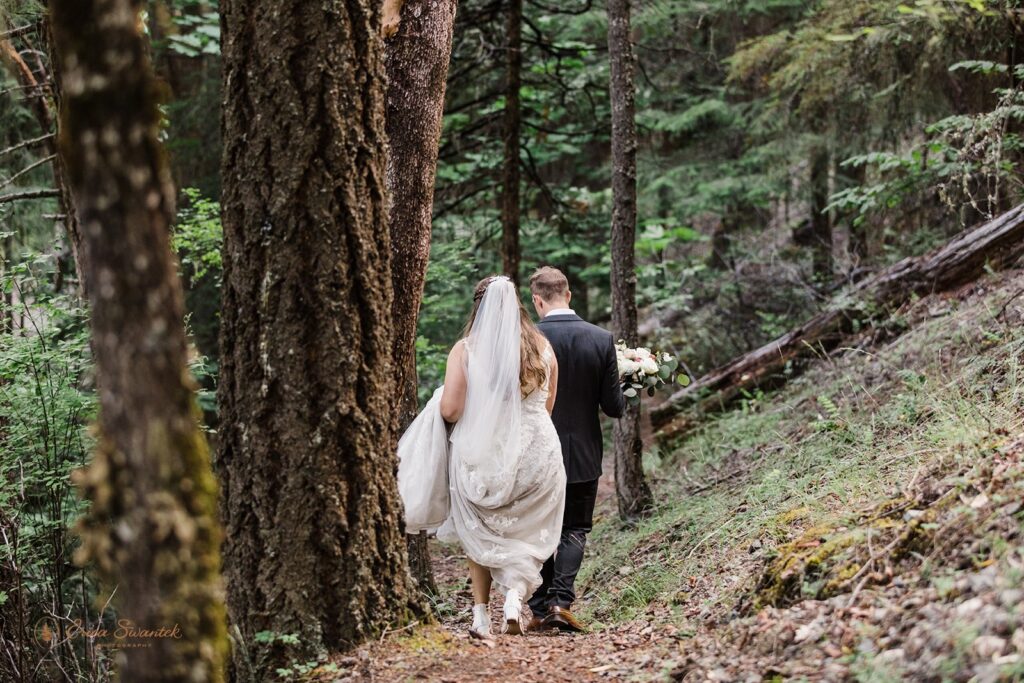 bride and groom hiking together through a lush forest in Oregon