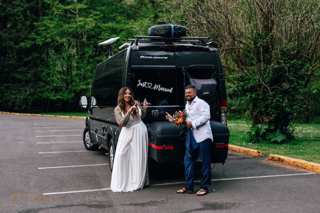 bride and groom standing by their mini van, decorated with just married signs