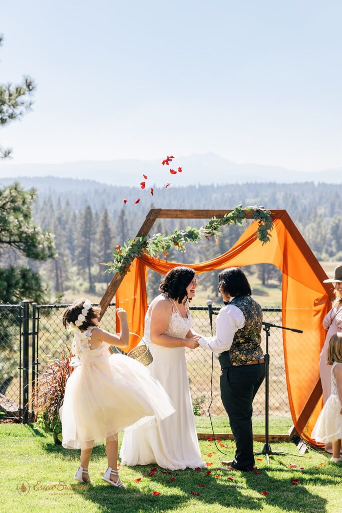 A flower girl tosses petals as her mom's wedding in Sisters, OR.