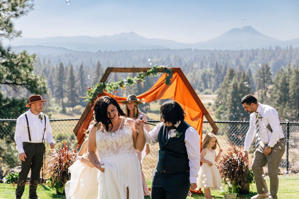 cheerful wedding couple heading off from their outdoor wedding ceremony