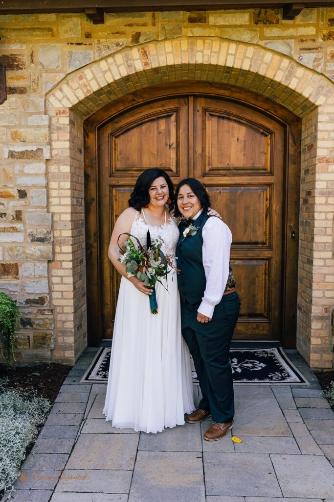 a beautiful lgbtq couple posing by a tuscan style house