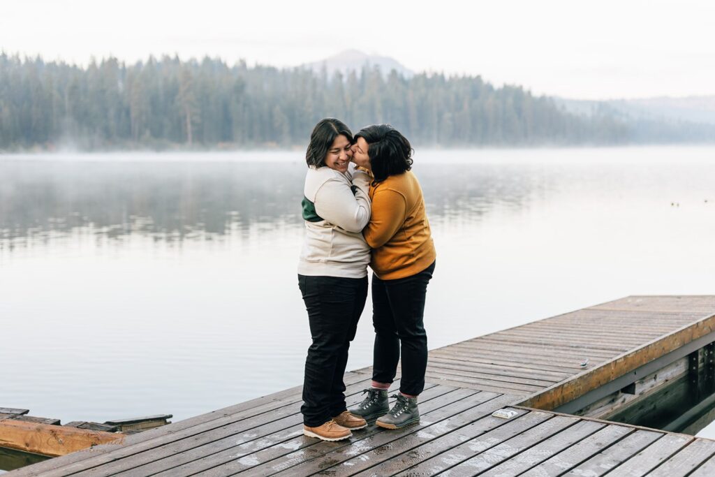 a romantic and playful lgbtq couple hugging by suttle lake at suttle lake lodge