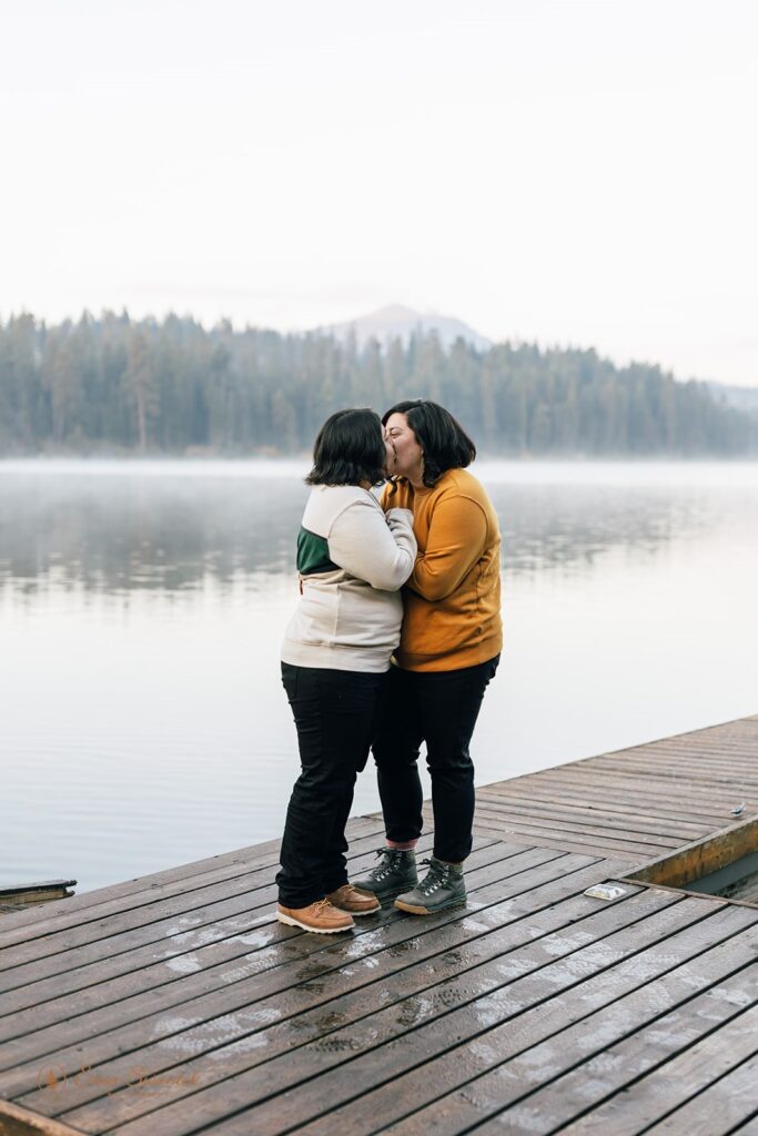 a romantic and playful lgbtq couple hugging by suttle lake at suttle lake lodge