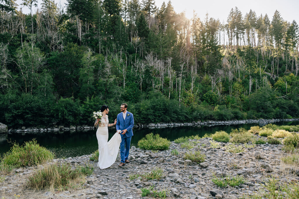A bride and groom walk along the banks of the Chetco River in Brookings, Oregon for their intimate wedding. 