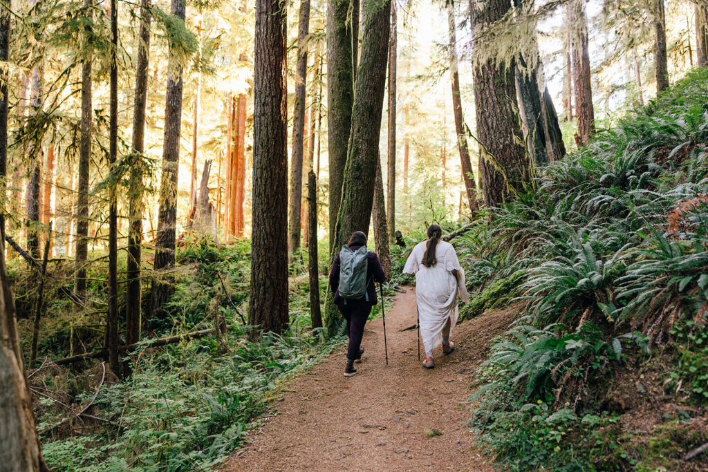 A couple hikes in their wedding attire through the morning sunlight on their Oregon elopement day.