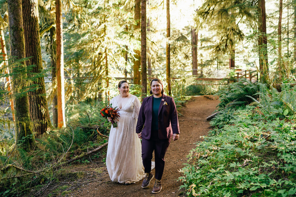 A couple hikes in their wedding attire through the morning sunlight on their Oregon elopement day.