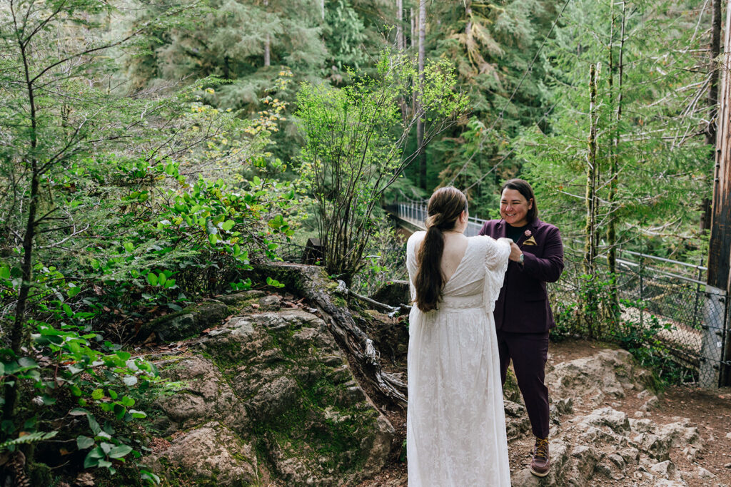 Two brides seeing each other for their first look at their waterfall elopement in Oregon. 