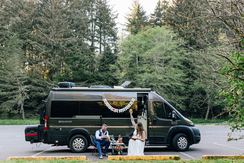 bride and groom standing by their adventure van, decorated with just married signs