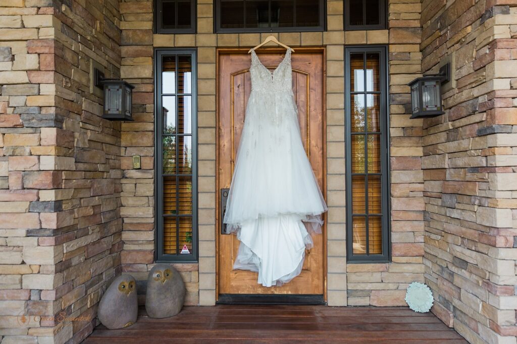 A beautiful wedding gown hangs on the door of a brick home in Bend, Oregon.