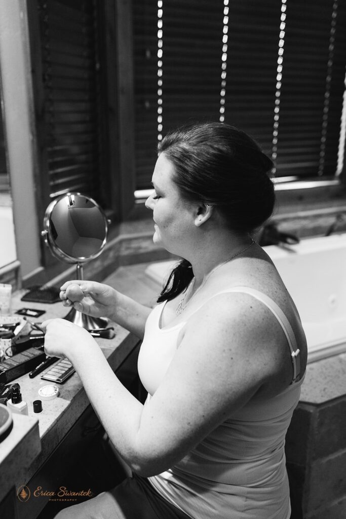 bride does her own makeup in front of the mirror