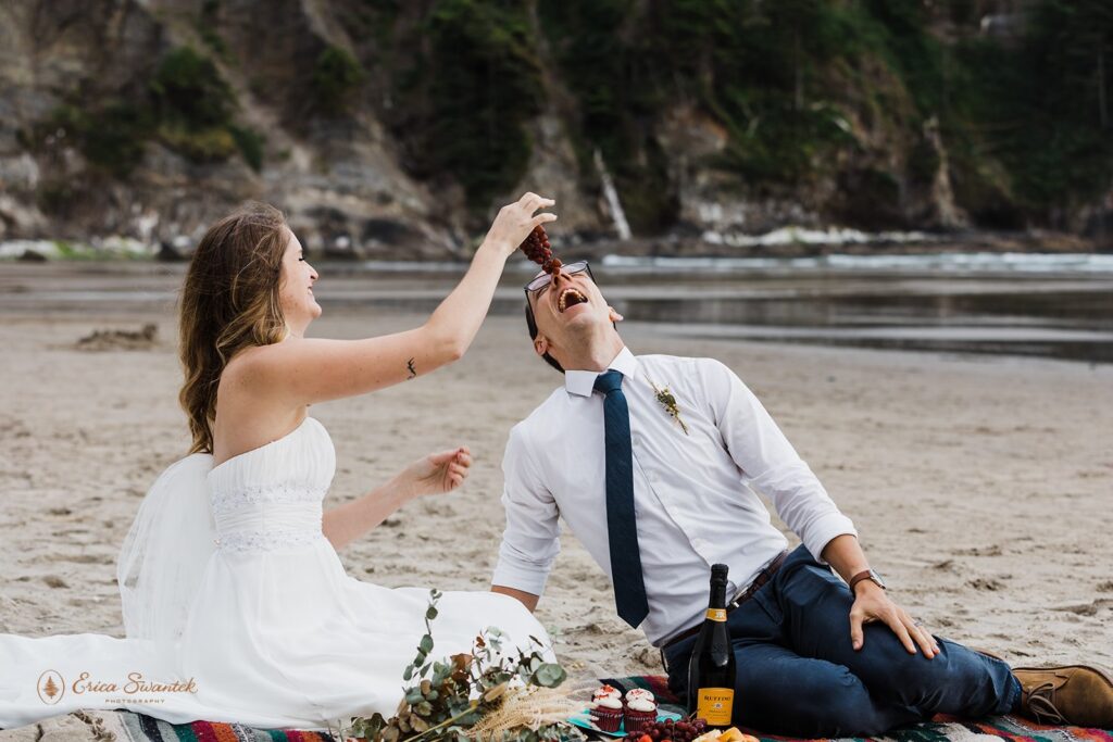 A bride feeds her husband grapes at their Oregon beach elopement.