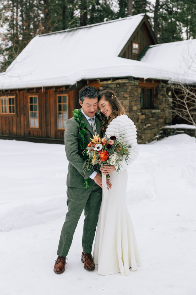 A couple snuggles in the snow at their winter Lake Creek Lodge wedding. 