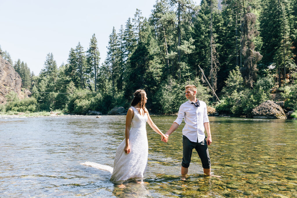A couple celebrates their Mt. Rainier National Park elopement by jumping in the Naches River. 