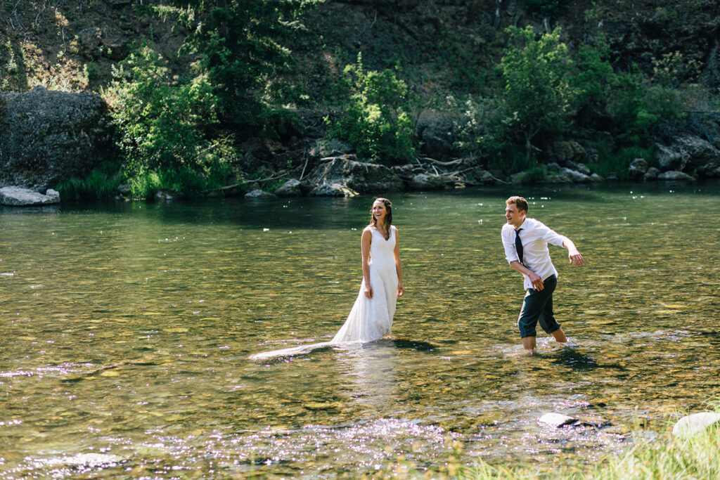 A couple celebrates their Mt. Rainier National Park elopement by jumping in the Naches River. 