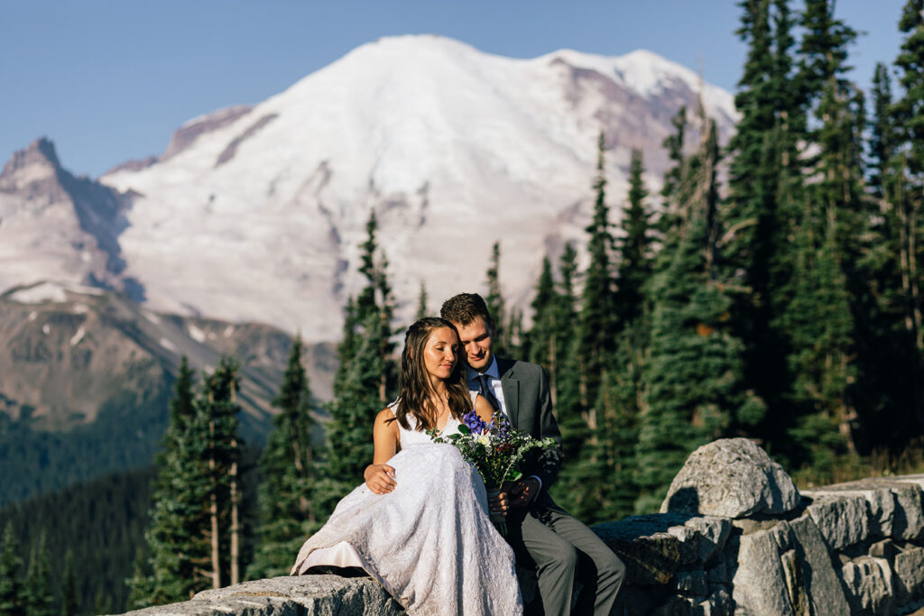 A couple sits in front of Mt. Rainier on their wedding day.