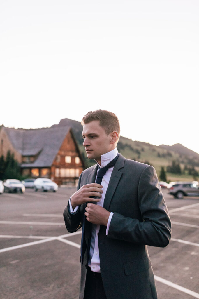 Groom putting on his tie at the trailhead.