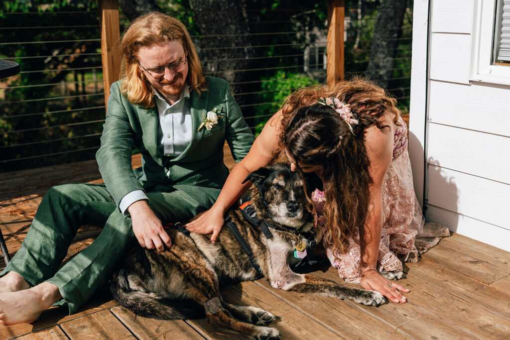 A wedding couple cuddles with their dog on their elopement day. 