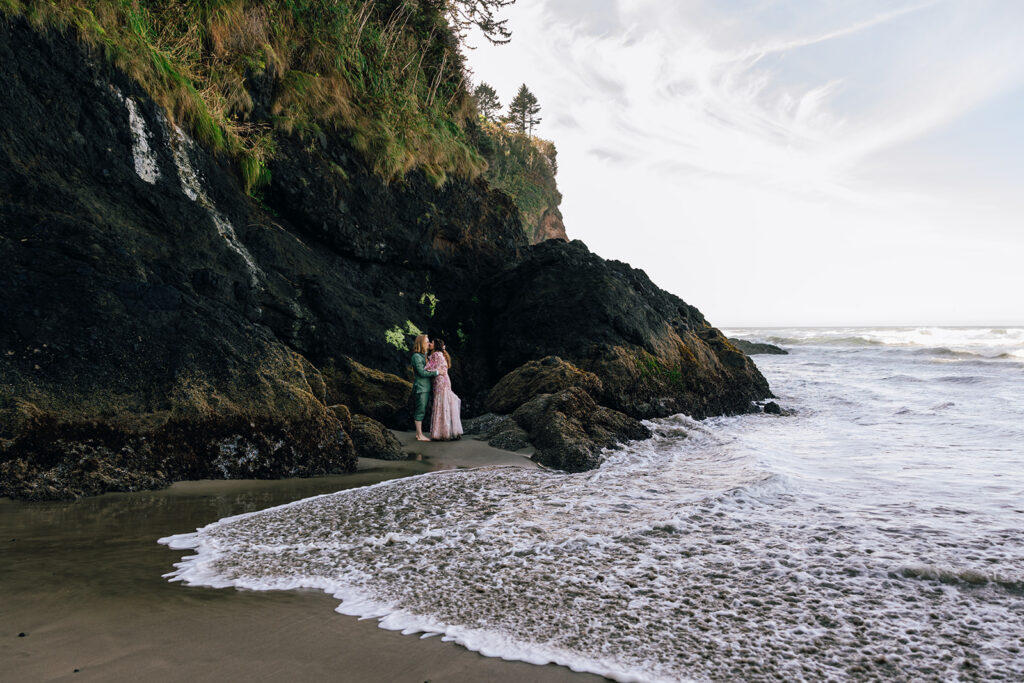 A wedding couple poses along the rocky beach in Oregon on their elopement day. 