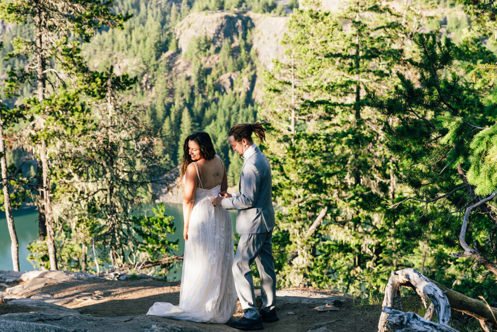 Groom zips up bride's dress for her Washington elopement. 