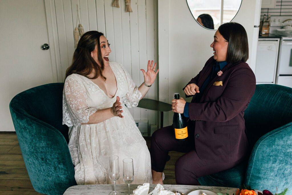 Two brides pop champagne on their elopement day.