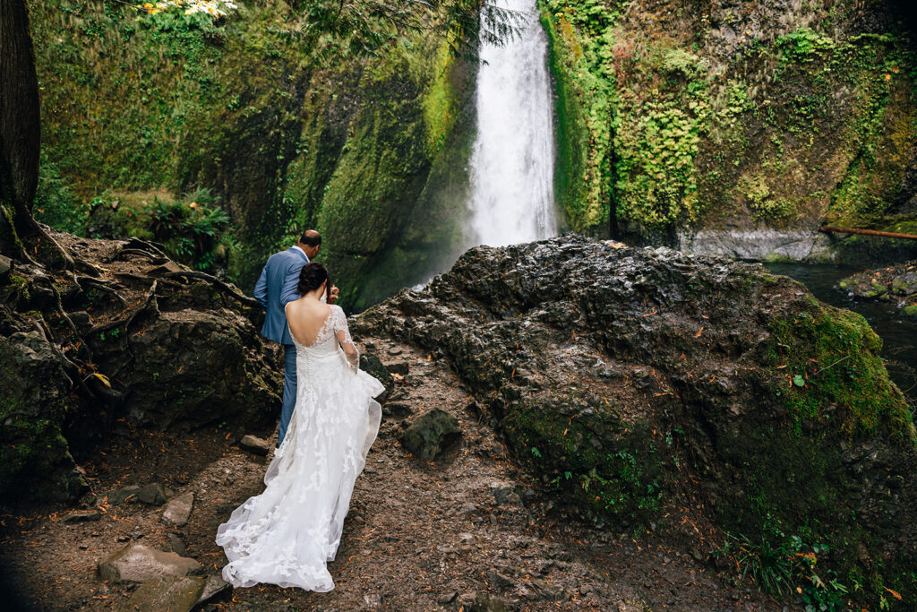 bride and groom hiking to a waterfall on their elopement day