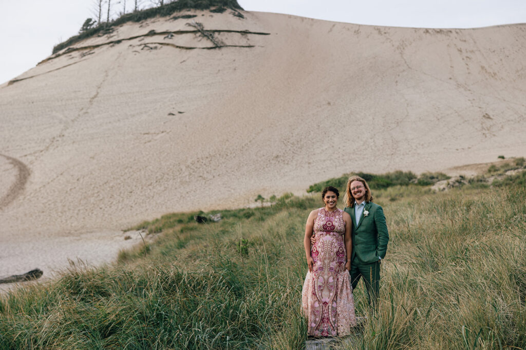 A wedding couple stands by the sandstone bluff of Cape Kiwanda in Pacific City, Oregon. 