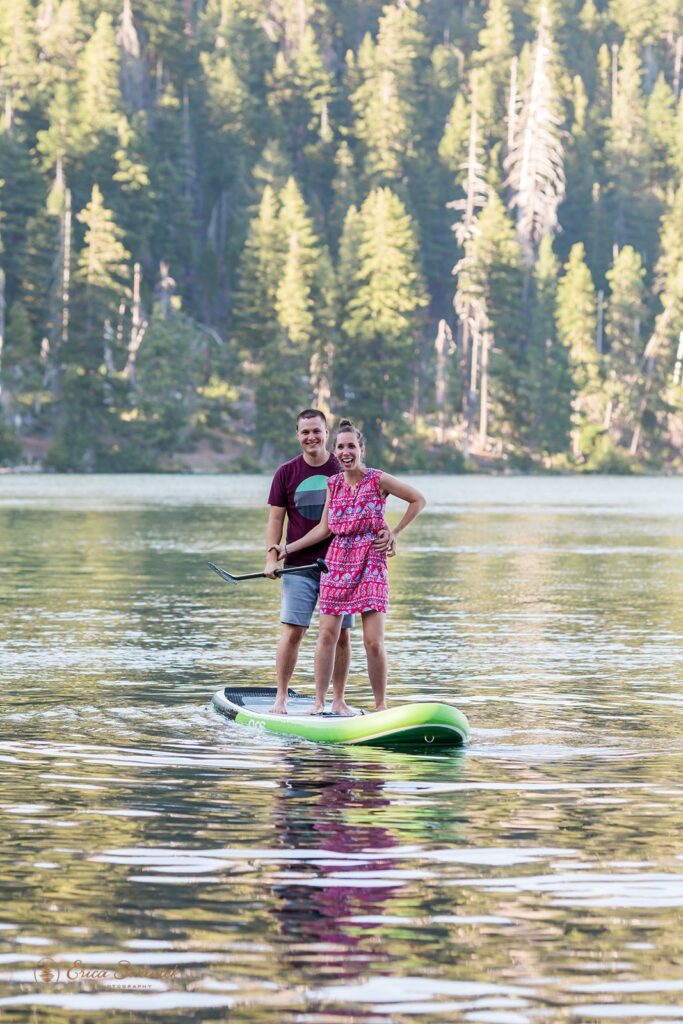 fun couple paddleboarding on a lake for their engagement session