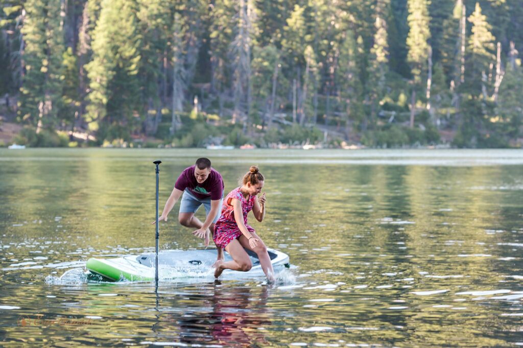 fun couple paddleboarding on a lake for their engagement session