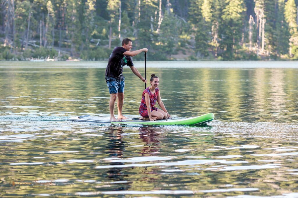 fun couple paddleboarding on a lake for their engagement session