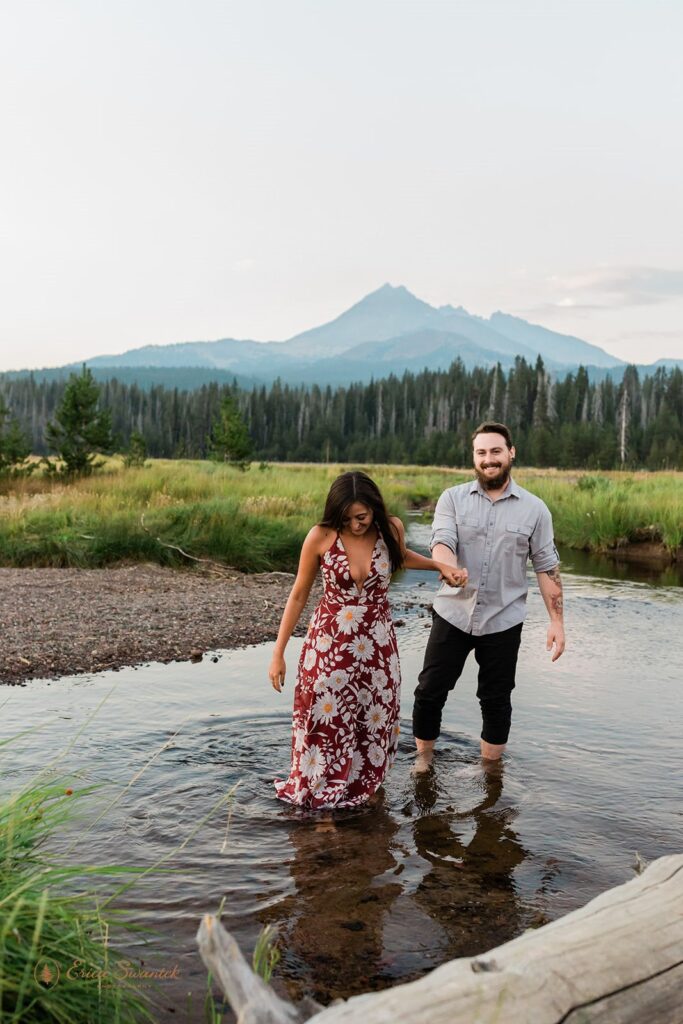 couple walking through a shallow water stream and being playful with each other