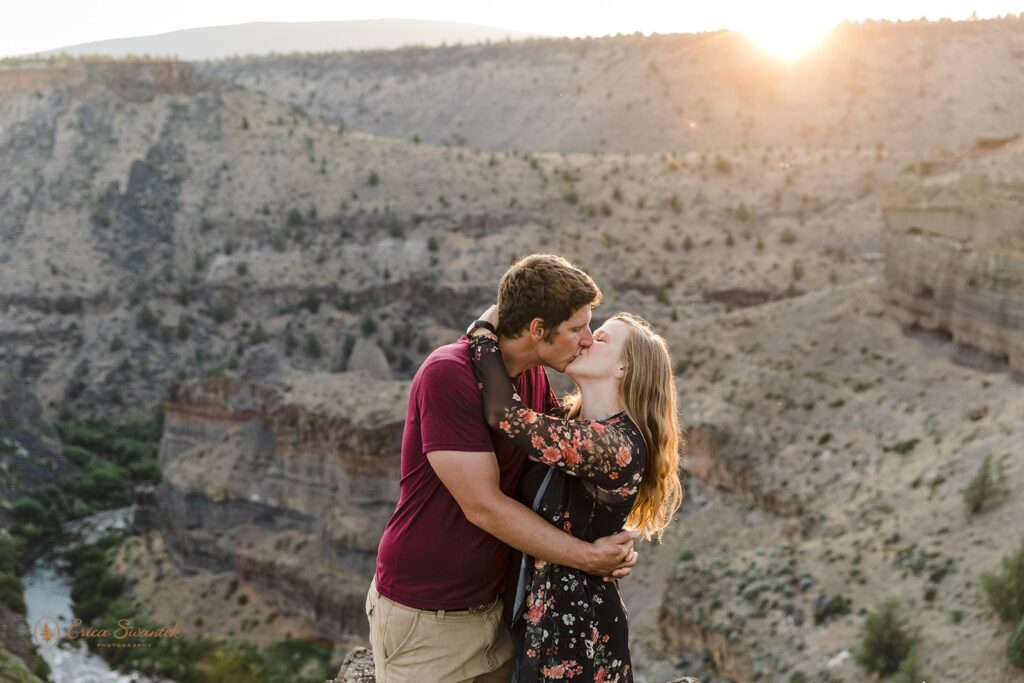 engaged couple kissing with sunset in the backdrop