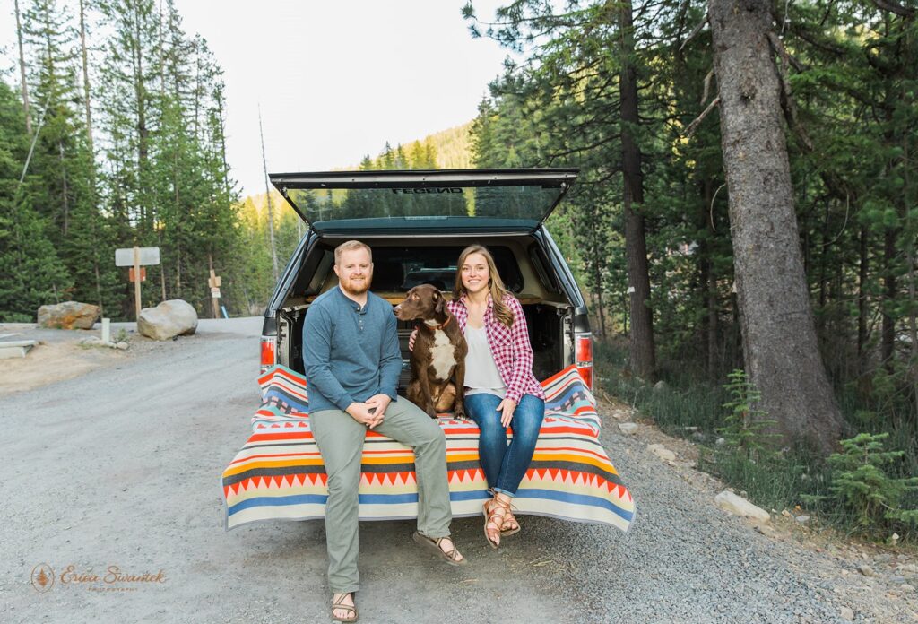 couple sitting at the back of their jeep with their pup