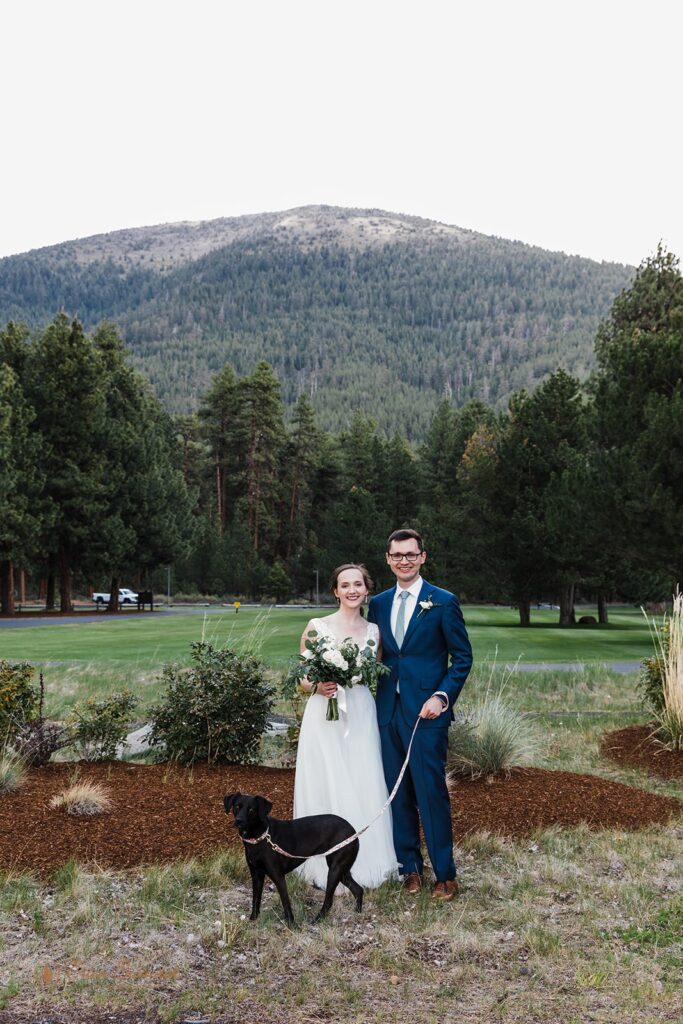 a romantic wedding couple with their dog with mountain views in the backdrop during their Black Butte Ranch wedding