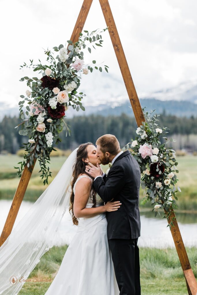 couple kissing at their A frame wedding arch after their black butte ranch wedding ceremony