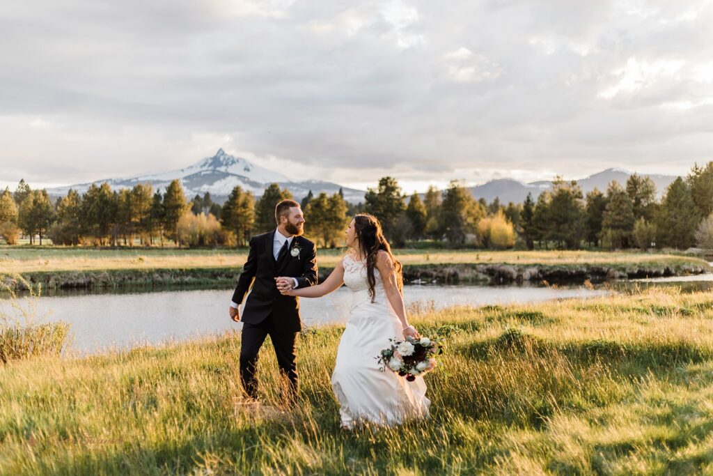 bride and groom roaming around a lush field during golden hour in Oregon