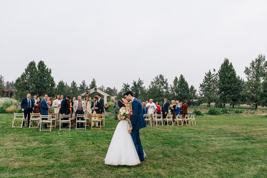 fun and cheerful wedding couple exiting their ceremony as guests cheer on in the backdrop