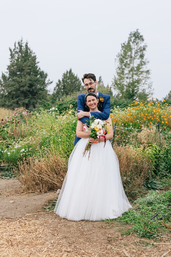 bride and groom hugging with flowers in the backdrop