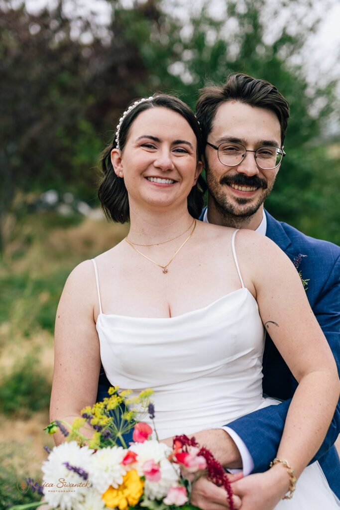 Close-up of the bride and groom smiling, with the bride holding a colorful bouquet of flowers