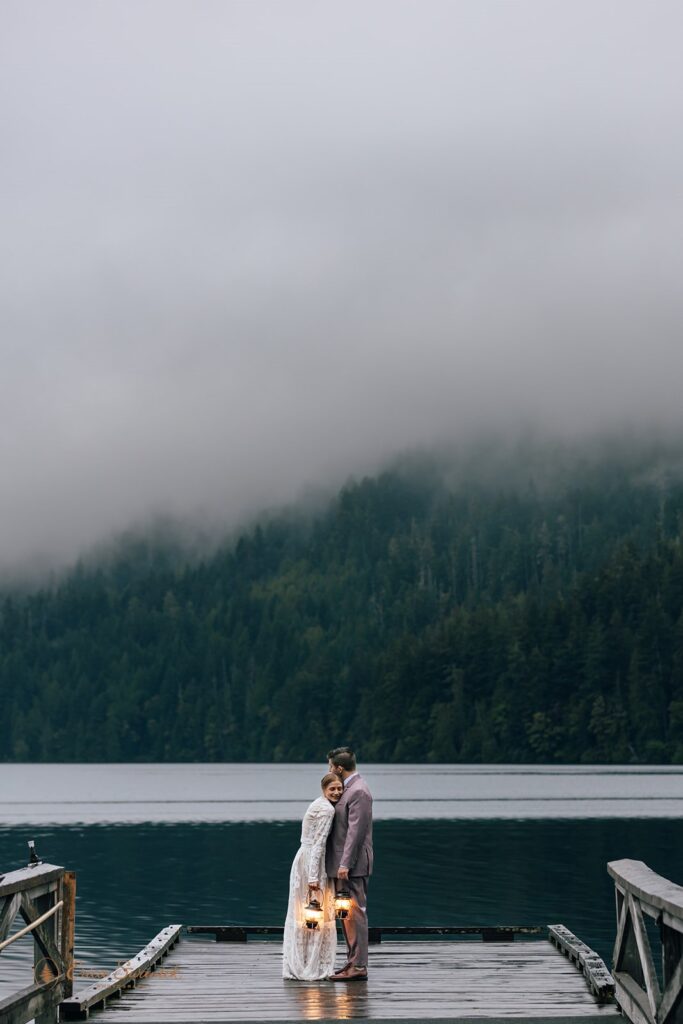 dreamy elopement couple standing with lanterns in hands before sunrise