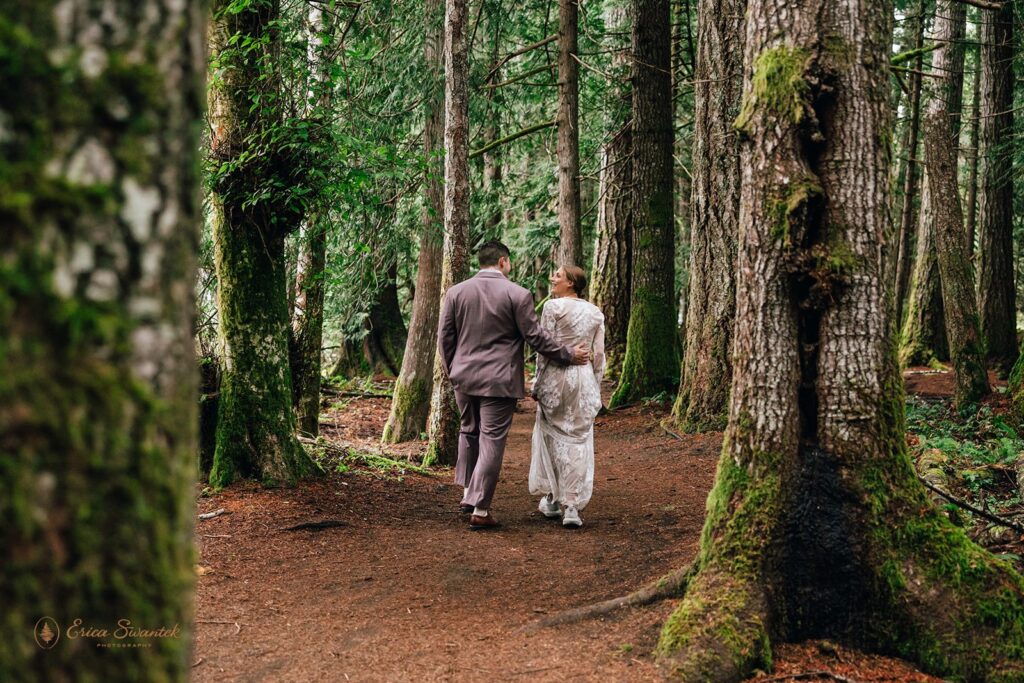 couple hiking through a lush forest in their elopement attire during their Olympic National Park elopement