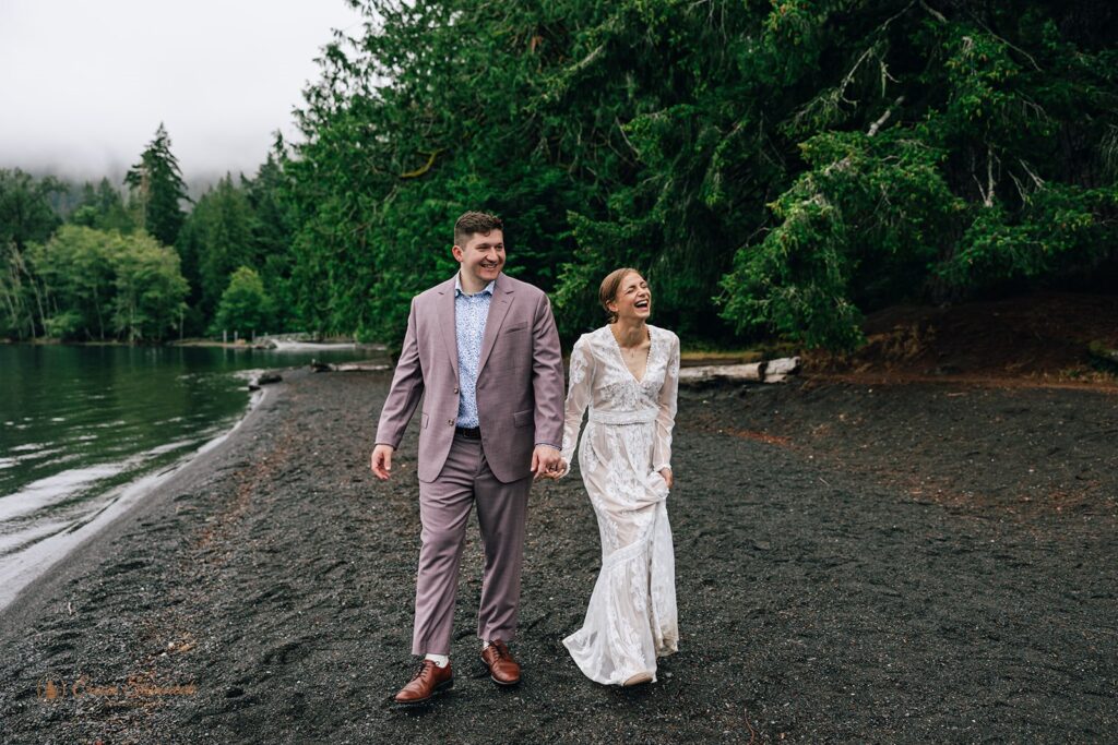 candid joyful elopement couple walking along the shore of lake crescent during their olympic national park elopement