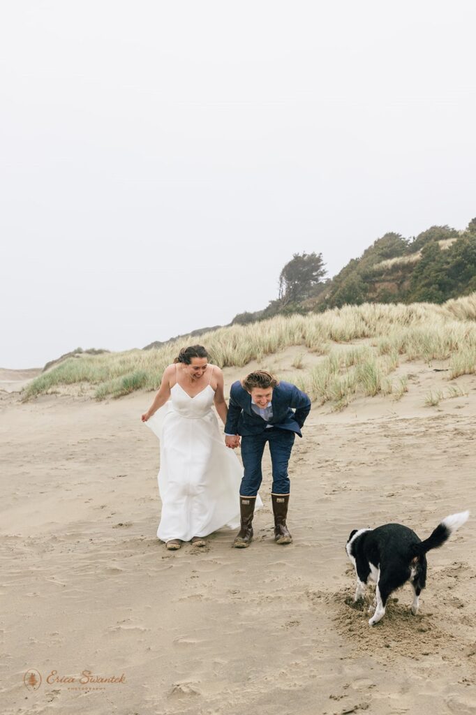 playful elopement couple with their dog at the beach shore