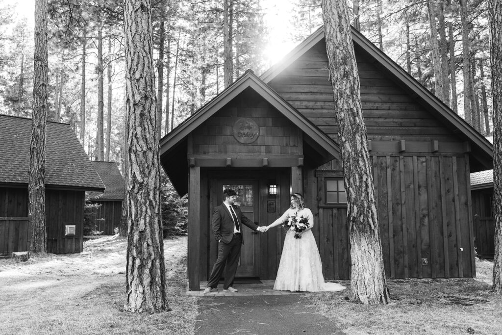 wedding couple holding hands in front of a cute rustic cabin