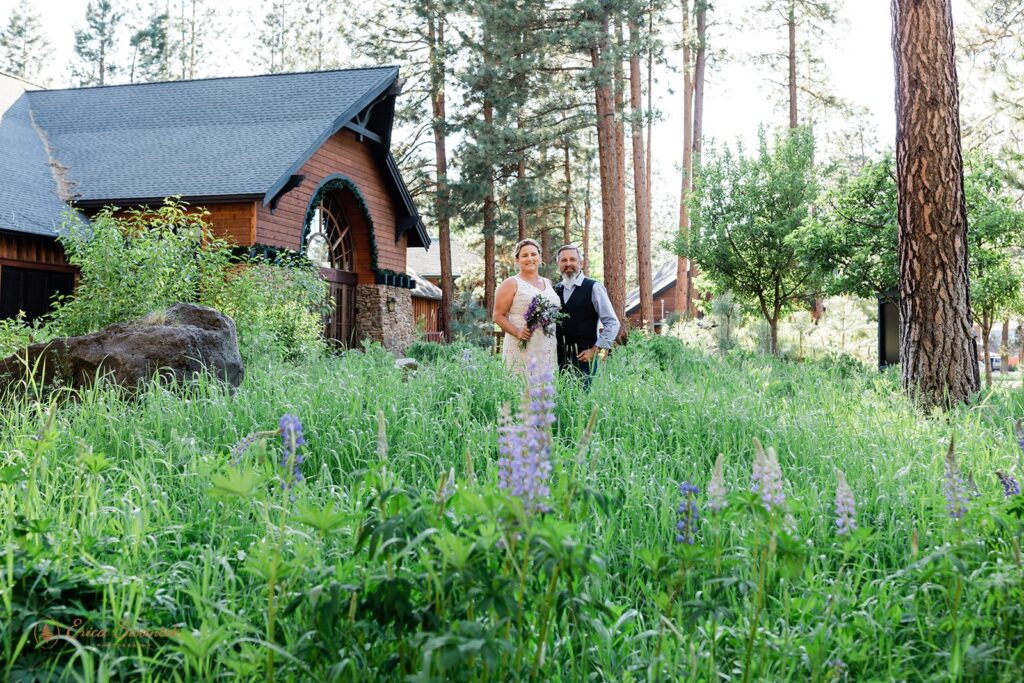 bride and groom with rustic cabins in the backdrop