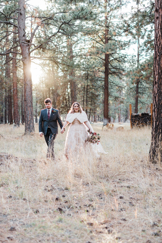 elopement couple walking through a forest together with sun shining through the tree tops