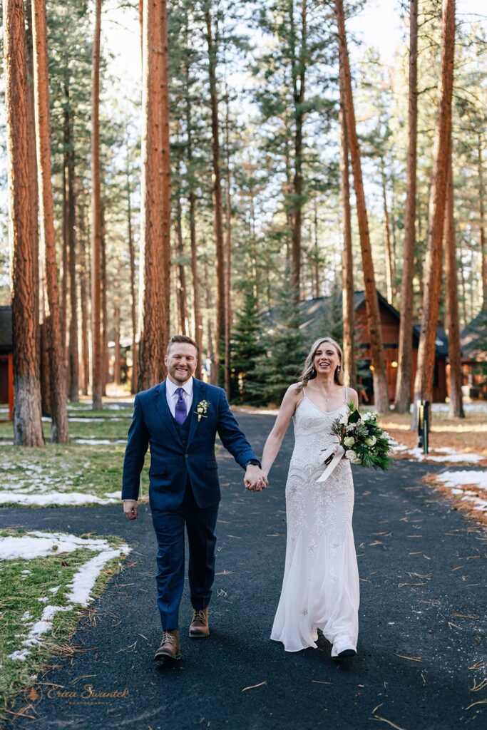 bride and groom walking hand in hand through a forested setting