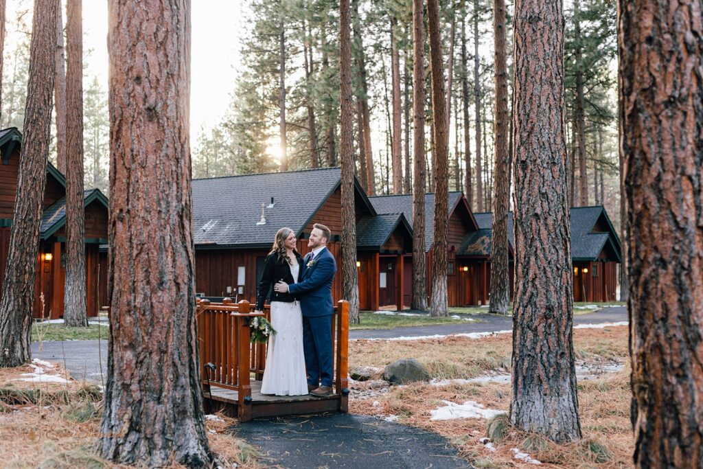 bride and groom with rustic cabins in the backdrop